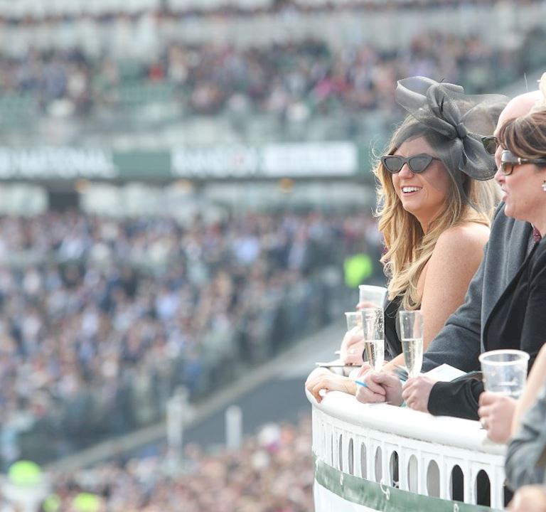 a women looking over the racecourse from a grandstand on a sunny day